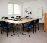 A meeting room with a dining table, blue chairs, a projector, and a screen in commercial premises.