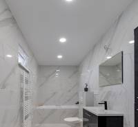 A bathroom in a family house with ceramic walls and a bathtub, a black sink, and a mirror.
