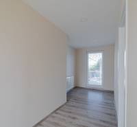 A hallway in a family house with a wooden decor floor and a large window.