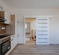 A kitchen in a family house with wooden decor, white built-in wardrobe, sliding doors.