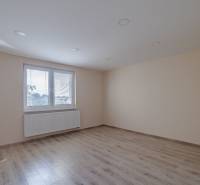 A room with a wooden floor design and a large window in a family house.