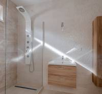 Bathroom with a shower and furniture with wood decor in a family house.