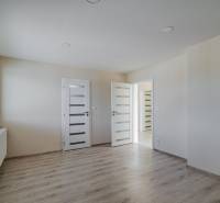 A room in a family house with a wooden decor floor, light walls, and a window.
