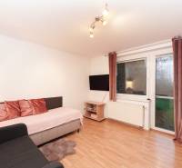 Living room in a family house with a sofa, television, and wooden decor flooring.