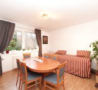 Dining room in a family house with a round table, chairs, a sofa, and a floor with a wooden decor.