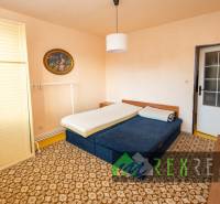 Bedroom in a 4-room apartment with a bed, ornamental carpet, and wardrobe.