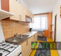 A kitchen in a 4-room apartment with simple furnishings, wooden cabinets, a stove, a window with a view.