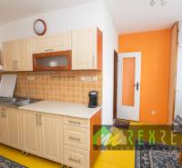 A kitchen with light cabinets and an orange wall in a 4-room apartment.