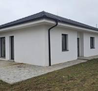 A family house in Cífer with a sloped roof and a paved terrace in the garden.