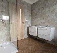 A bathroom in a family house with stone cladding and a shower enclosure.