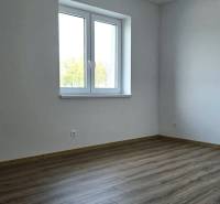 A room in a family house with a wooden decor floor and white walls.