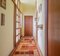 A hallway in a family house with carpet flooring, wooden doors, and decorations on the walls.