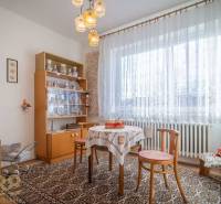 Dining room in a family house with carpet, wooden furniture, and decorations on the shelves.