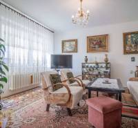 Living room in a family house with a sofa, TV, and paintings on the walls.