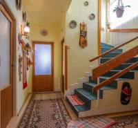 Interior of a family house with carpet, wall decorations, and a wooden staircase.