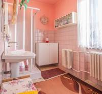 A bathroom in a family house with tiles and a shower, light pink walls.