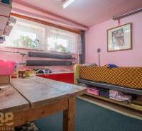 A room in a family house with pink walls, a wooden table, and a bed.