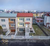 A family house in Poprad with double roofs, a white fence, and a landscaped garden.