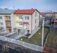 A family house in Poprad, with a colorful facade and a simple front garden, near apartment buildings.