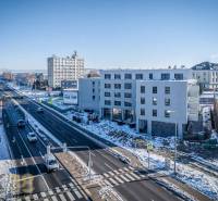 A building in Poprad by a busy road, snowy landscape, blue sky.