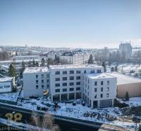 A building in the city of Poprad surrounded by a snowy landscape and other structures.