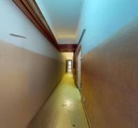 A narrow corridor with light at the end and smooth walls in commercial premises.