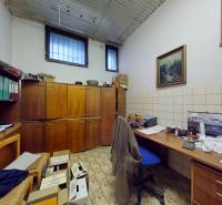 An office with wooden cabinets, a desk, and shelves, featuring tiles with a geometric pattern.