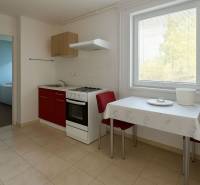A kitchen with a red cabinet, a table, and two chairs in a family house.