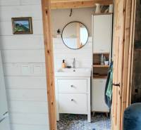 A bathroom in a family house with a round mirror and patterned tiles.