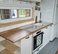 A kitchen in a family house with white cabinets, a wooden countertop, and patterned tiles.