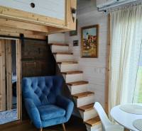 Interior of a family house with a blue armchair, wooden staircase, and floor with a wooden decor.