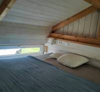 Attic bedroom with wooden beams and a small window in a family house.