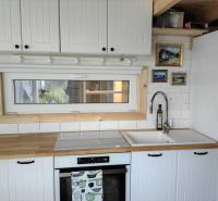 A kitchen in a family house with wooden decor, white cabinets, and a window.
