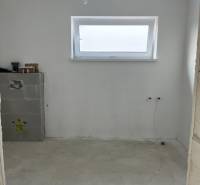 An empty room in a family house with wooden decor and a narrow window on the wall.