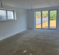 Empty room in a family house with large windows and a concrete floor.
