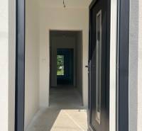 A hallway in a family house with white walls, view into the garden.