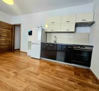 A kitchen in a 2-room apartment with a wooden decor floor and furnishings.