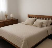A bedroom with wooden furniture, a bed, and decorative pillows, muted colors.