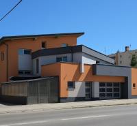 A building in Šaľa with a modern design, an orange-gray facade, and large windows.
