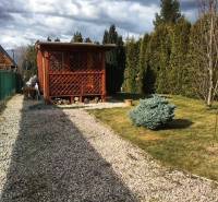 Wooden cottage in Kráľová nad Váhom with a landscaped garden and a bush.