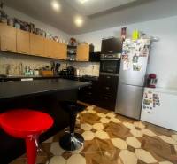 A kitchen with a decorative floor, kitchen cabinets, and appliances in a family house.
