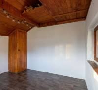The interior of a cabin with white walls, a wooden ceiling, and a floor with a wooden decor.