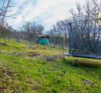 A trampoline and a cottage in the garden in Prešov, surrounded by trees and grass.