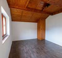 A room in a cottage with a wooden ceiling and a floor with a wooden decor.
