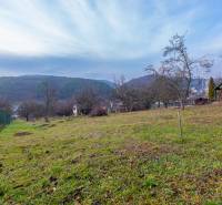 A garden with a view of the hills and a cottage in Prešov, surrounded by trees and a fence.