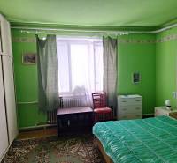 Green room in a family house with a bed, wardrobe, and carpet.
