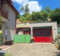 A family house in Tachtoch with an entrance gate, a garage, and surrounding greenery.
