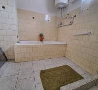 Bathroom in a family house with a bathtub and tiled walls.