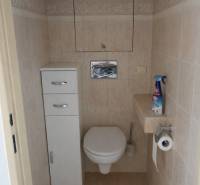 A toilet in light tiles in a 3-room apartment with storage space.