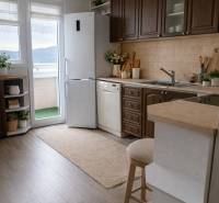 A kitchen with dark cabinets and a refrigerator in a 3-room apartment, floor with wood decor.